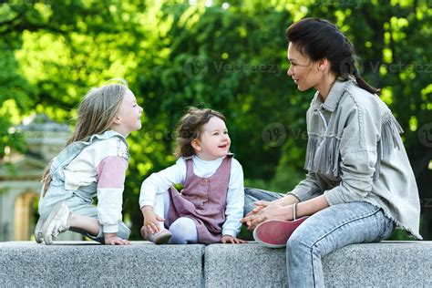 Mère Heureuse Et Ses Deux Filles Assises Et Jouant Dans Un Parc De La Ville 16248348 Photo De