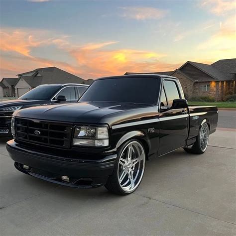 Two Black Trucks Parked In Front Of A House