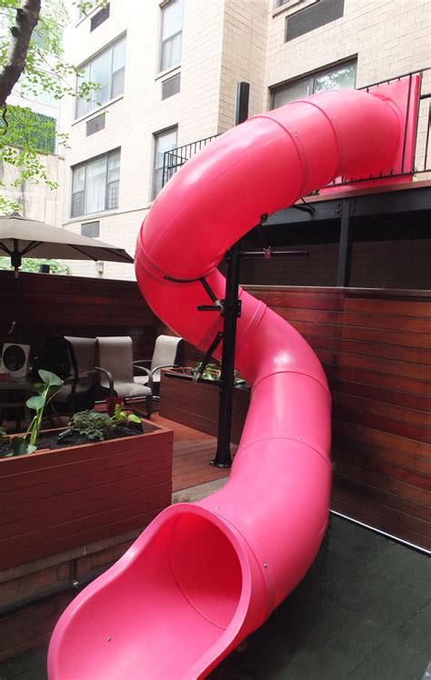 A Large Pink Slide In The Middle Of A Yard Next To A Building With Lots