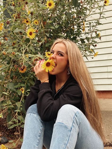 A Woman Sitting On The Ground With Sunflowers In Her Hand And Looking Up