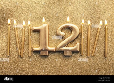 Number 12 Gold Celebration Candle On A Glitter Background Stock Photo