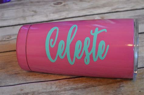 A Pink Cup With The Word Celeget On It Sitting On A Wooden Table