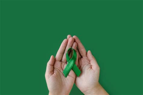 Premium Photo Adult Hands Holds Green Ribbon On Green Background