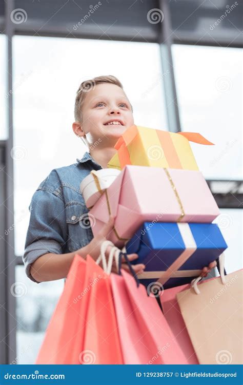 Muchacho Feliz Que Sostiene Las Cajas Coloreadas Con Las Bolsas De