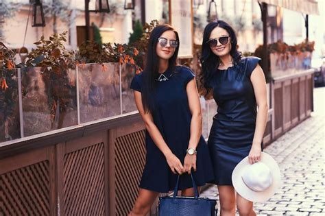 Free Photo Two Sexy Brunette Wearing Stylish Black Dresses In Sunglasses Posing Near A