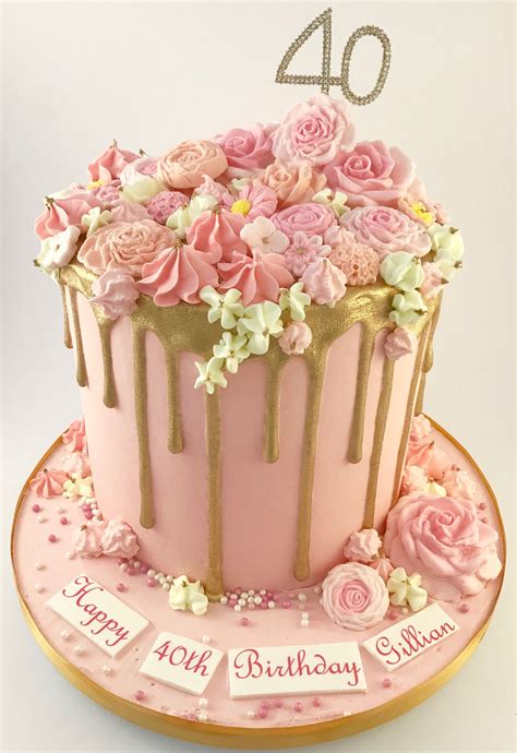 A Birthday Cake With Pink Flowers And Gold Drips On Its Top Is Sitting