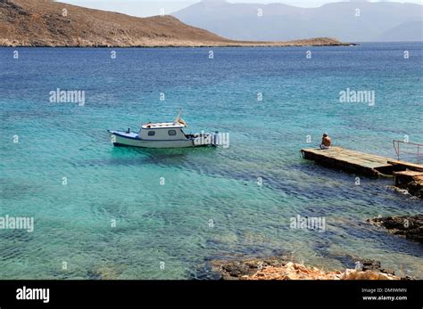 Traditional Halki Fishing Boat Next To A Wooden Jetty And Crystal Clear