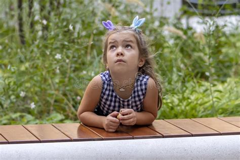 A Blonde 5 Year Old Girl Looks Up Pensively Against A Backdrop Of