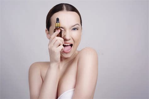 Close Up Of Model Brunette Girl With Cosmetic Oil On Her Face With Pipette The Girl Shows