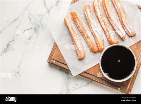 Board With Tasty Churros And Melted Chocolate Sauce On Light Background