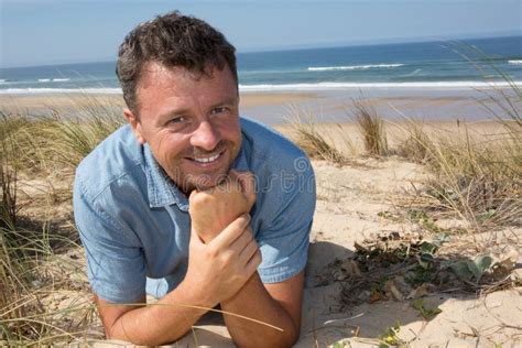 Smiling Handsome Man Relaxing On The Beach Lying On Sand Stock Image