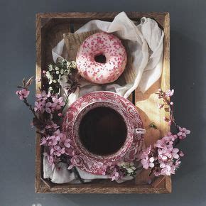 A Pink Donut Sitting On Top Of A Table Next To A Cup Of Coffee