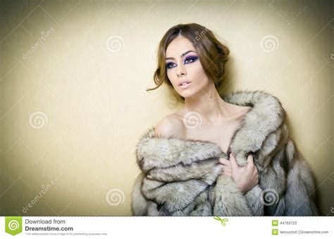 Attractive Young Woman Wearing A Fur Coat Posing Provocatively Indoor