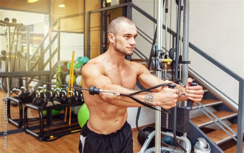 Muscular Bodybuilder With Naked Torso Exercises In Cable Crossovers