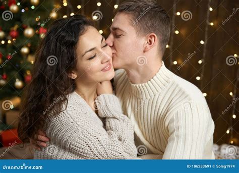 Couple In Christmas Lights And Decoration Dressed In White Young Girl And Man Fir Tree On