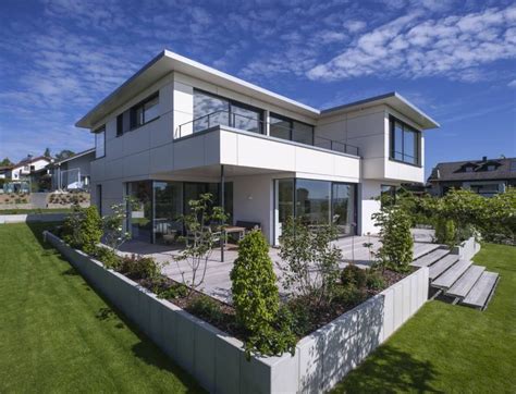 A Modern House With An Outdoor Deck And Garden Area In The Foreground