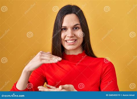 Young Hispanic Woman Standing Over Yellow Background Gesturing With Hands Showing Big And Large