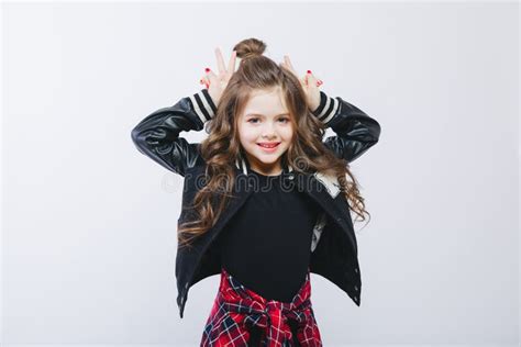 Portrait Of Little Hipster Girl In Bomber Jacket Showing Horns By Hands