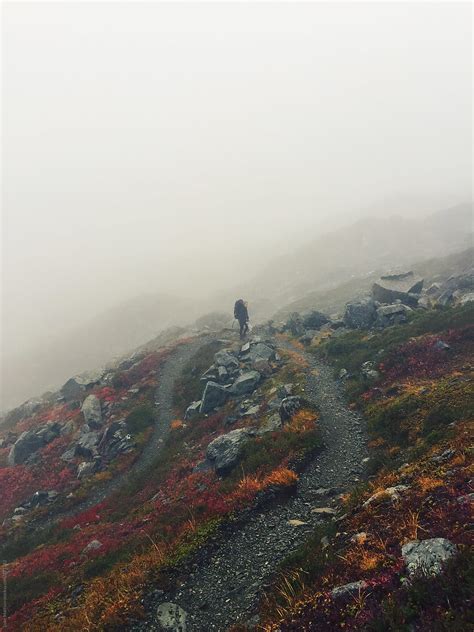 «Solo Hiker Climbing Winding Mountain Path Through The Fog» del colaborador de Stocksy «Luke ...