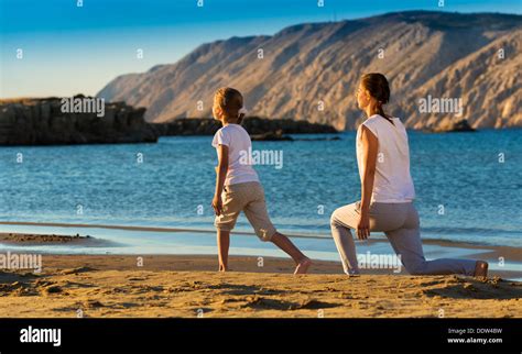 Mother and daughter doing yoga exercise on the beach Stock Photo - Alamy