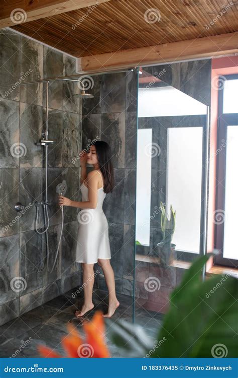 Brunette Femenina De Pie En Ducha Con El Vestido De Noche Sosteniendo La Cabeza De Ducha Imagen