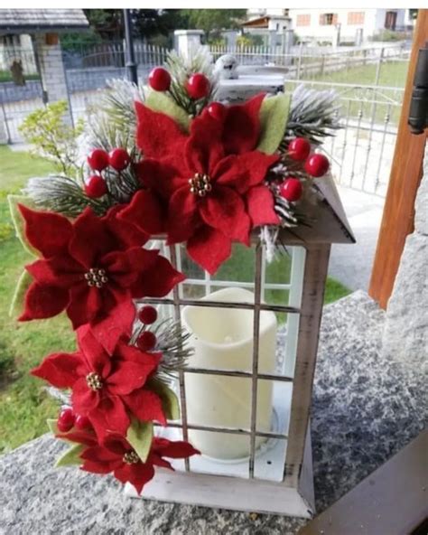 A Lantern With Poinsettis And Greenery On It