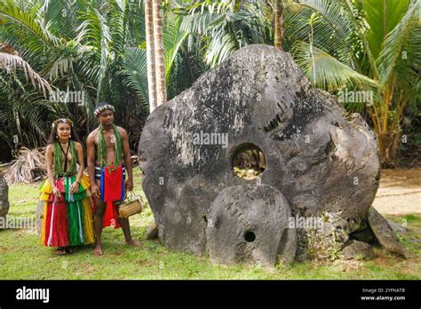 Native Yapese couple in traditional clothing, pictured with stone money in their village on the ...