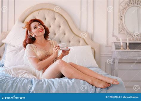 A Luxurious Pin Up Lady Dressed In A Beige Vintage Lingerie Posing In