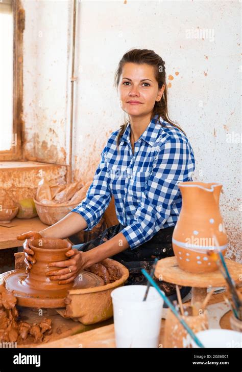 Portrait Of Adult Female Potter Working With Clay On Pottery Wheel In