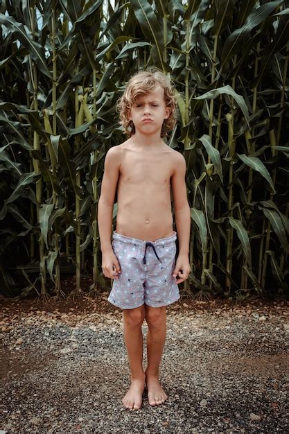 Premium Photo Displeased Boy Standing Against Green Corn Plantation