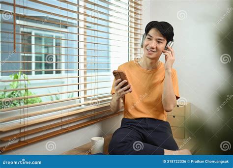 Portrait Of Positive Young Asian Man Listening To Music In Headphones