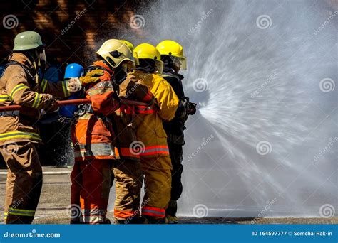 Brave Firefighter Using Extinguisher And Water From Hose For Fire