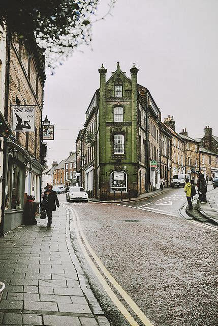 People Walking Down The Street In Front Of Some Buildings