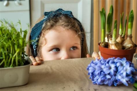 Garota transplanta flores e planta uma criança em uma bandana planta