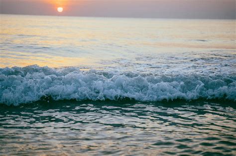 A sunset over the ocean with a person on the beach · Free Stock Photo