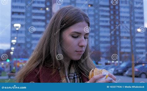 Young Woman Standing In An Urban Street And Eating Burger Young Woman