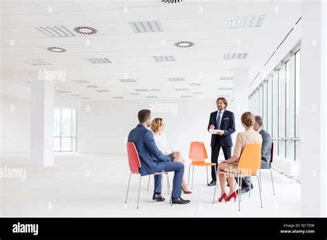 Mature Businessman Discussing With Colleagues Against Window In New