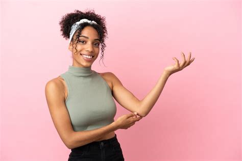 Jovem latina isolada em um fundo rosa estendendo as mãos para o lado para convidar para vir