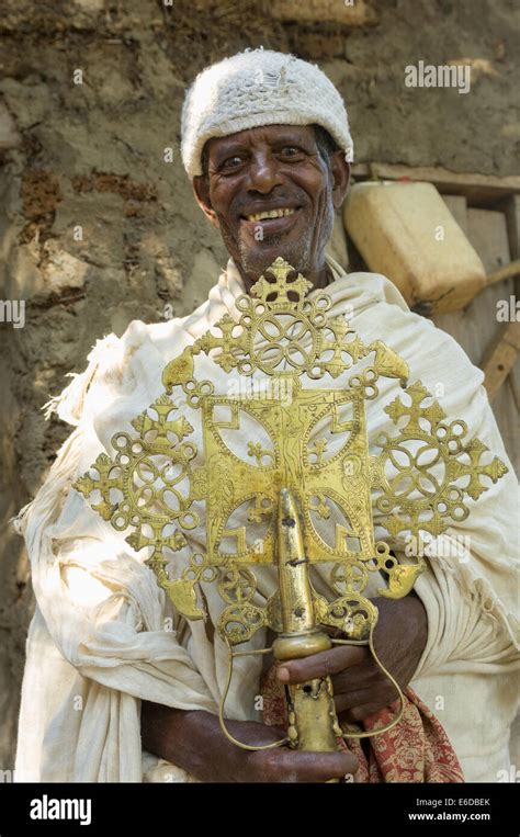 Grinning Priest Holding An Ethiopian Cross Outside Of The Church Of