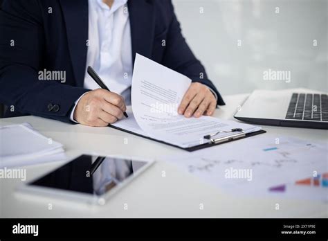 Asian Mature Man In A Business Suit Signing Important Documents At An