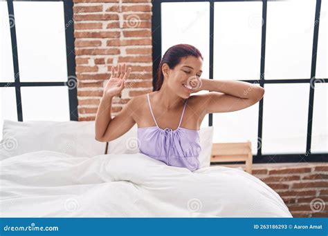 Young Beautiful Hispanic Woman Waking Up Stretching Arms At Bedroom