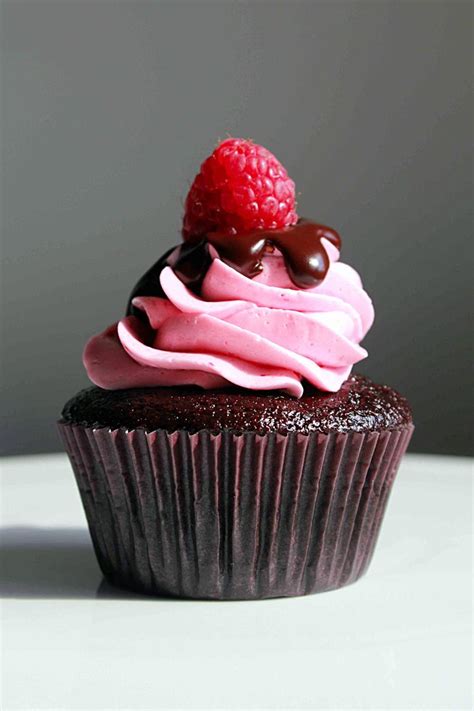 A Chocolate Cupcake With Pink Frosting And A Raspberry On Top