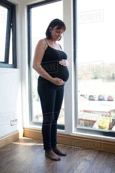 Mature Pregnant Woman Looking Out Of Window At Home Stock Photo Dissolve