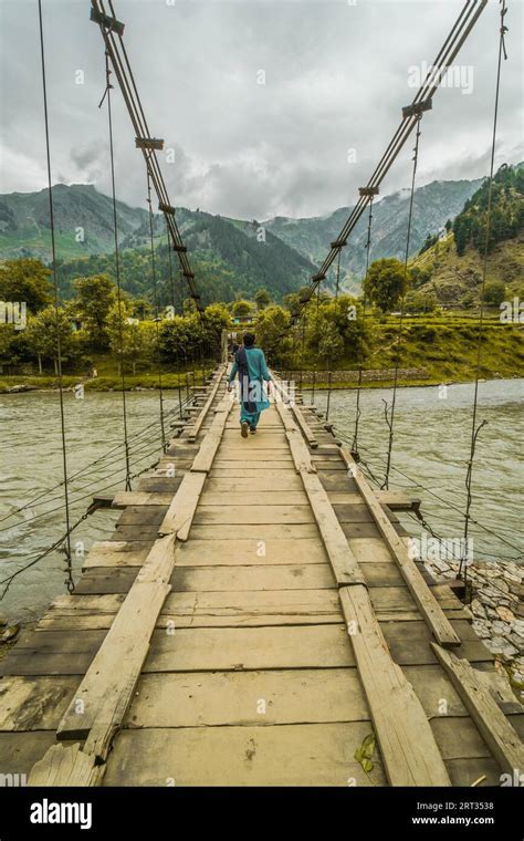 A Woman Crossing River Indus On Dangerously Looking Bridge In Pakistan