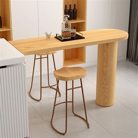 A Kitchen Table With Two Stools In Front Of It And Bottles On The Shelf