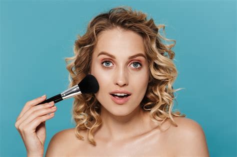 Premium Photo Beautiful Half Naked Woman Applying Makeup With Powder Brush Isolated Over Blue Wall