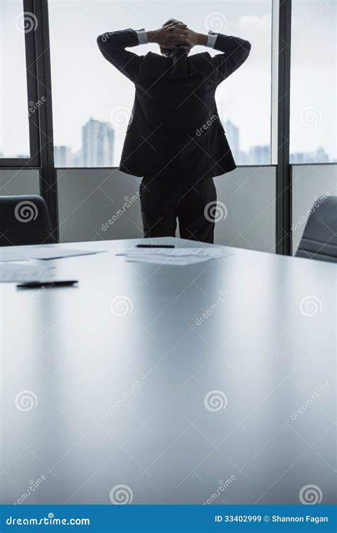 Overworked Businessman With Hands Behind His Head Looking Out The