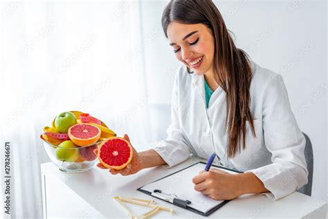 Foto De Portrait Of Young Smiling Female Nutritionist In The