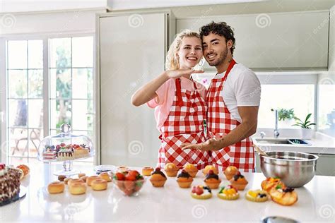 Couple Of Wife And Husband Cooking Pastries At The Kitchen Gesturing With Hands Showing Big And