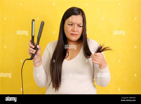 Adult Latina Woman With Very Long Straight Hair Combs Her Hair With A Straightener Worried About